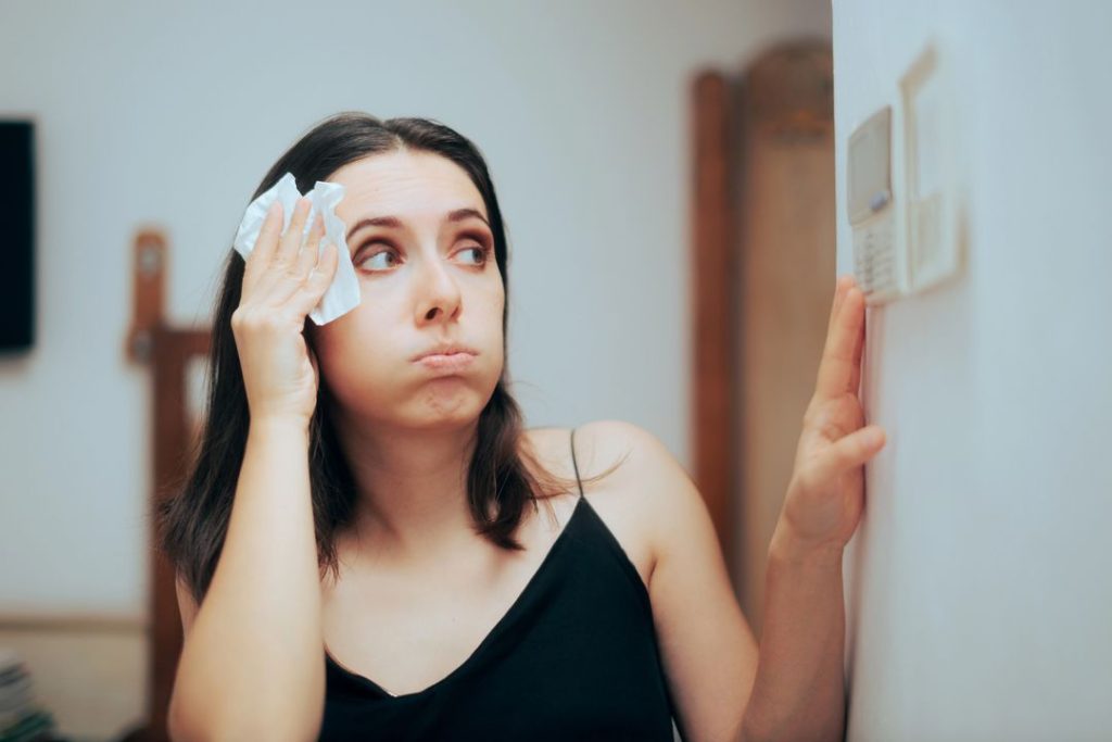 A woman is cleaning her face with a towel in front of a mirror.