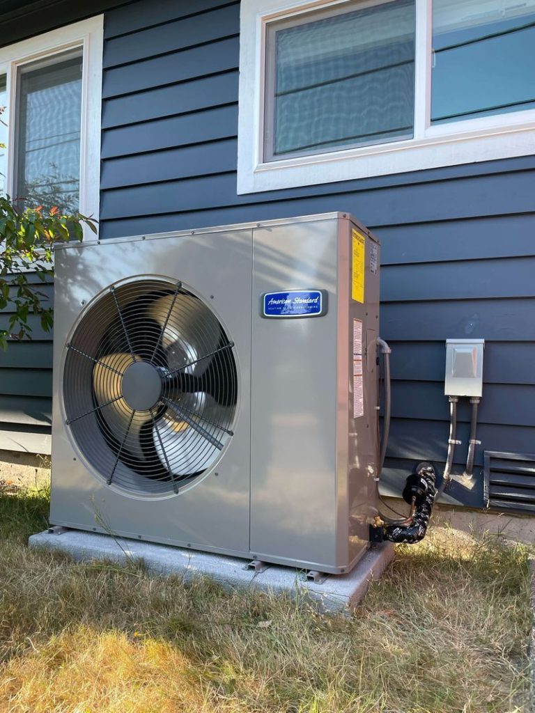 A large fan is sitting on the side of a house.